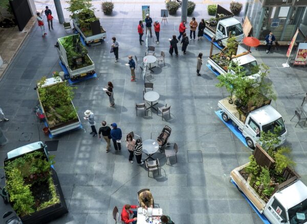 Aerial image of several small white kei-trucks, each with a Japanese style garden constructed in their cargo-beds. Via Spoon and Tamago blog.